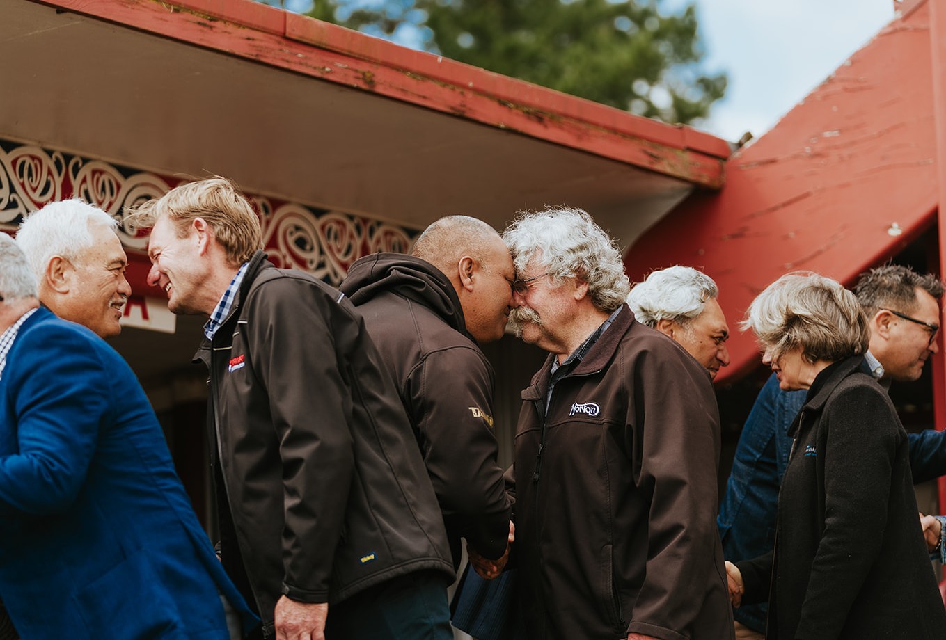 Māori people in front of a marae performing a hongi