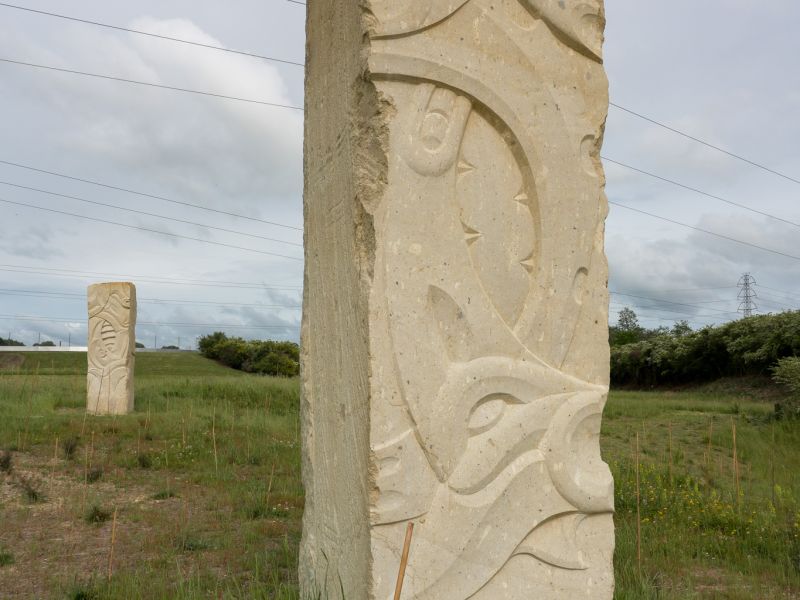 A sandy coloured block of stone carved with Māori designs